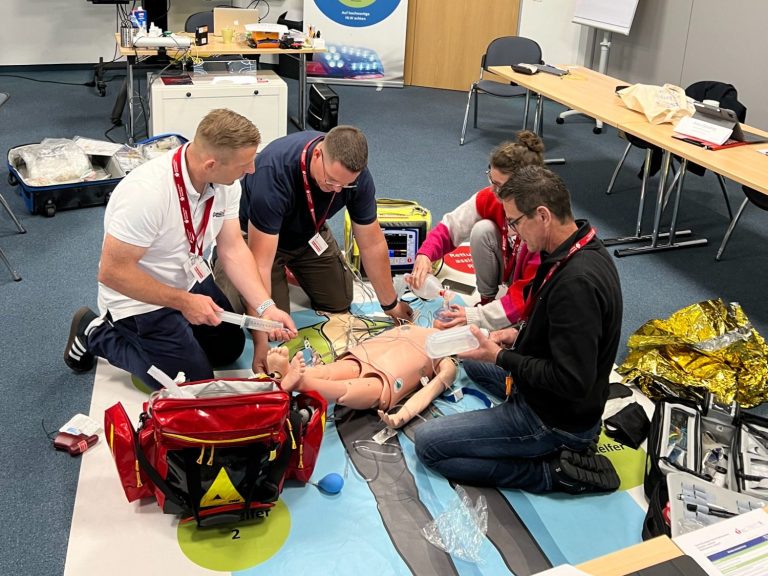 Praktisches Notfalltraining im Team Teilnehmende üben gemeinsam an einer Übungspuppe im Notfalltraining.